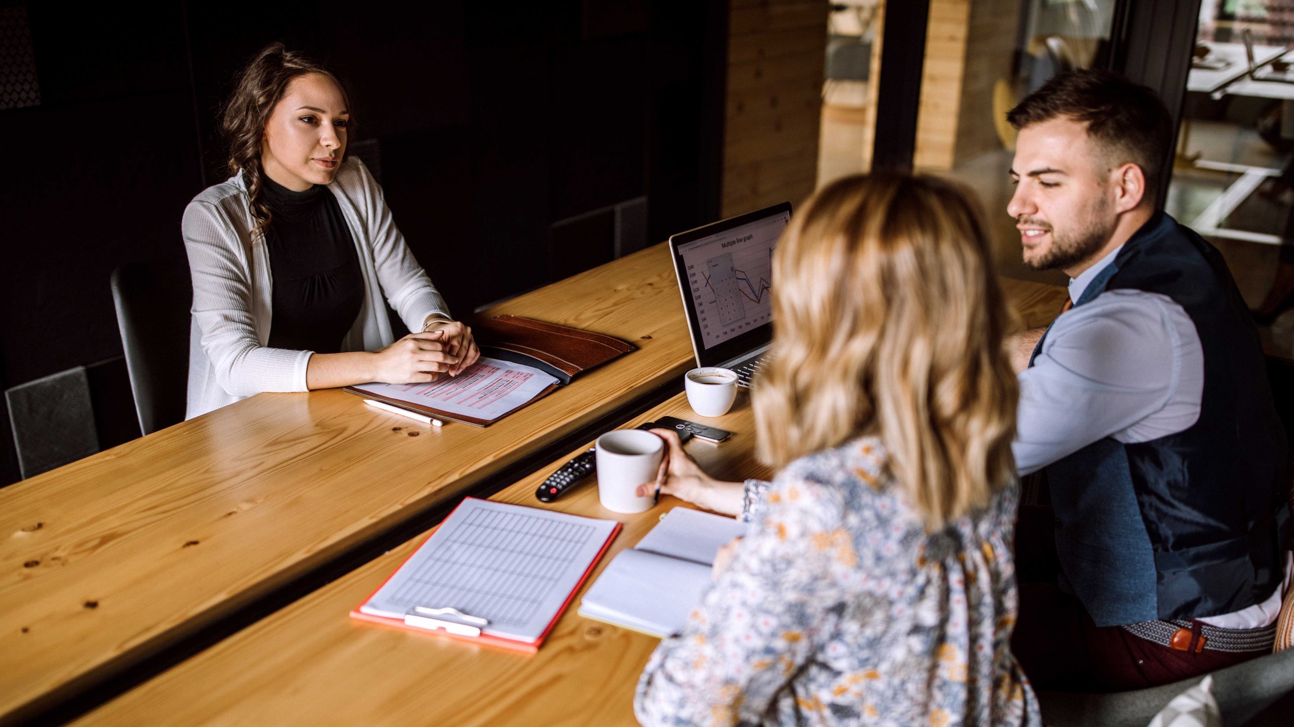 Man accompanied with two women sitting in board room and having business interview